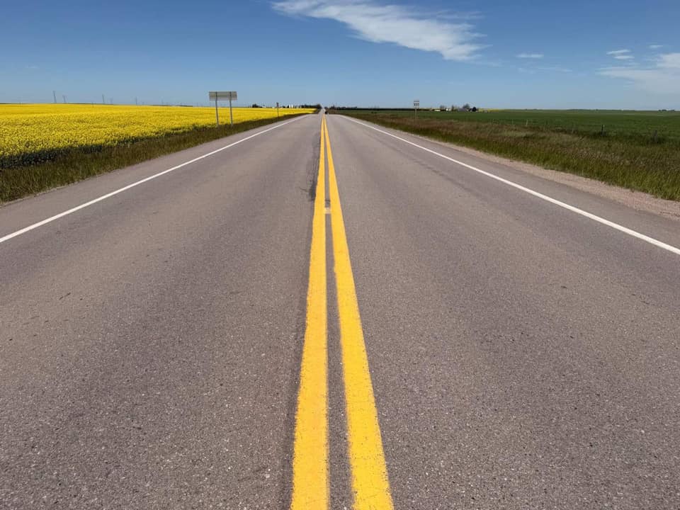A straight prairie highway running between fields