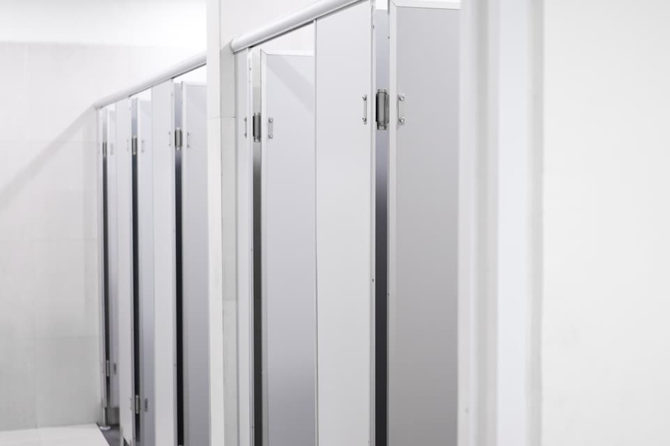 A row of cubicle partitions in a commercial washroom