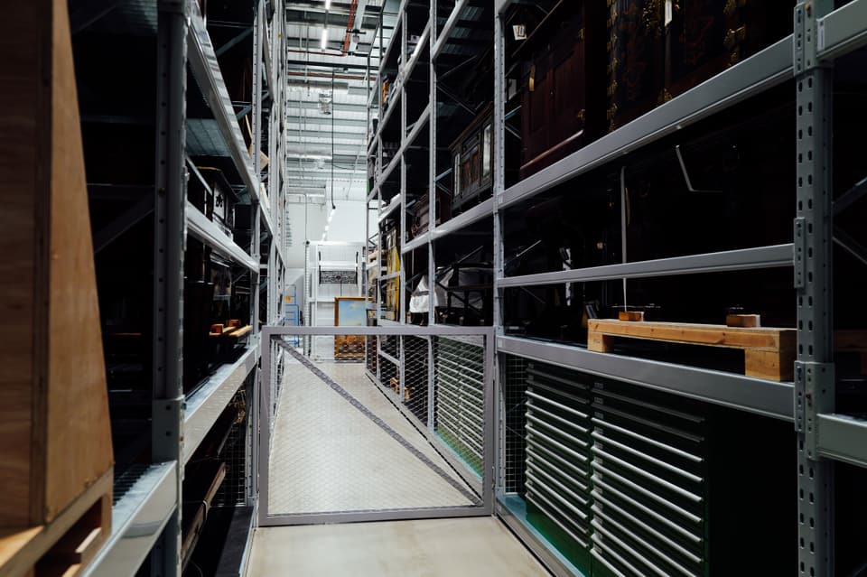 A narrow aisle between tall warehouse racking stacked with stock
