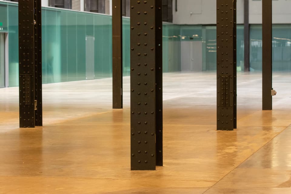 A large industrial interior with steel pillars and a polished concrete floor